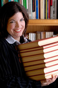 a smiling library assistant with a stack of books